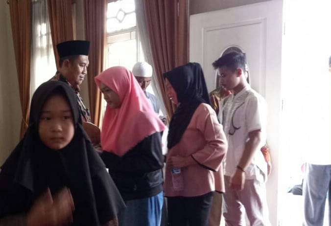 H. Nasrulloh, SE (berpakaian batik dan berpeci hitam) sedang memberikan santunan kepada masyarakat 4 RT